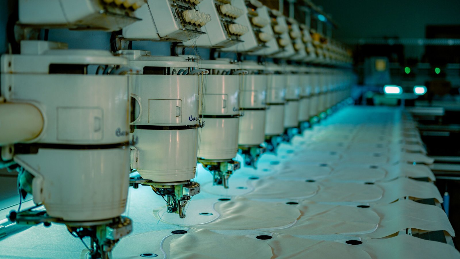 Home Row of industrial sewing machines in a textile factory producing garments.