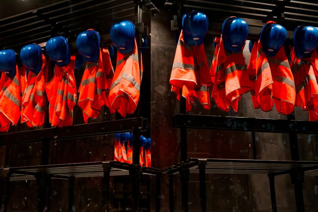 Home Row of orange safety vests and blue helmets hanging in industrial setting